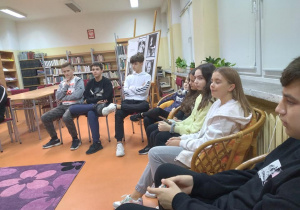 Uczniowie siedzą w kręgu w budynku Miejskiej Biblioteki Publicznej Filia "Siódemka".